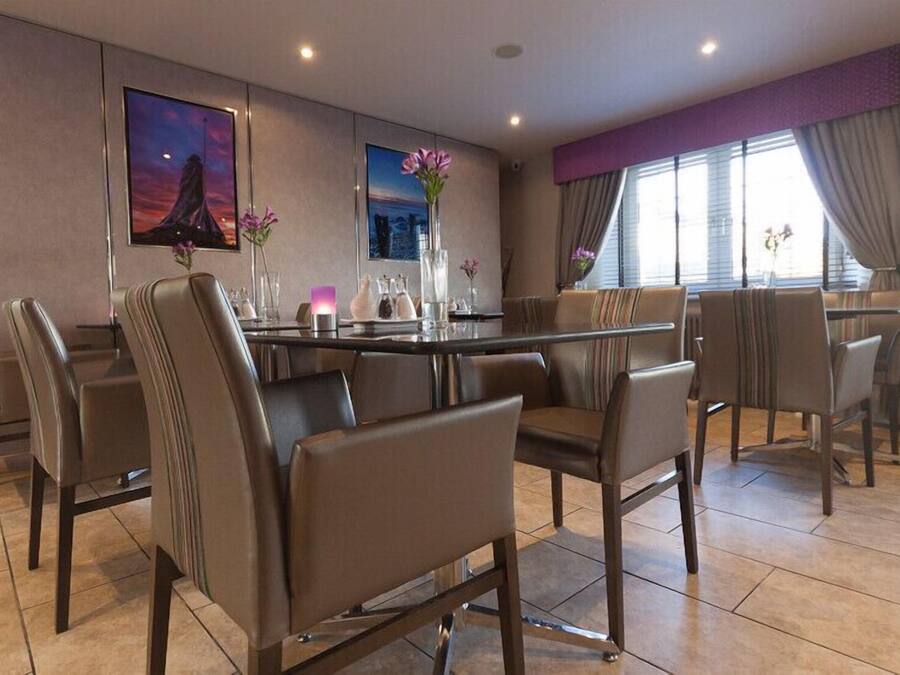 A modern dining area with a round table, leather chairs, and artwork on the walls.