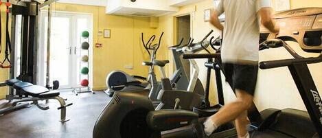 A gym with exercise equipment including a bench, a squat rack, and treadmills.