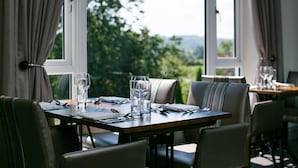 A dining table set for two with a view of greenery outside. - The Plough Rhosmaen (Llandeilo)