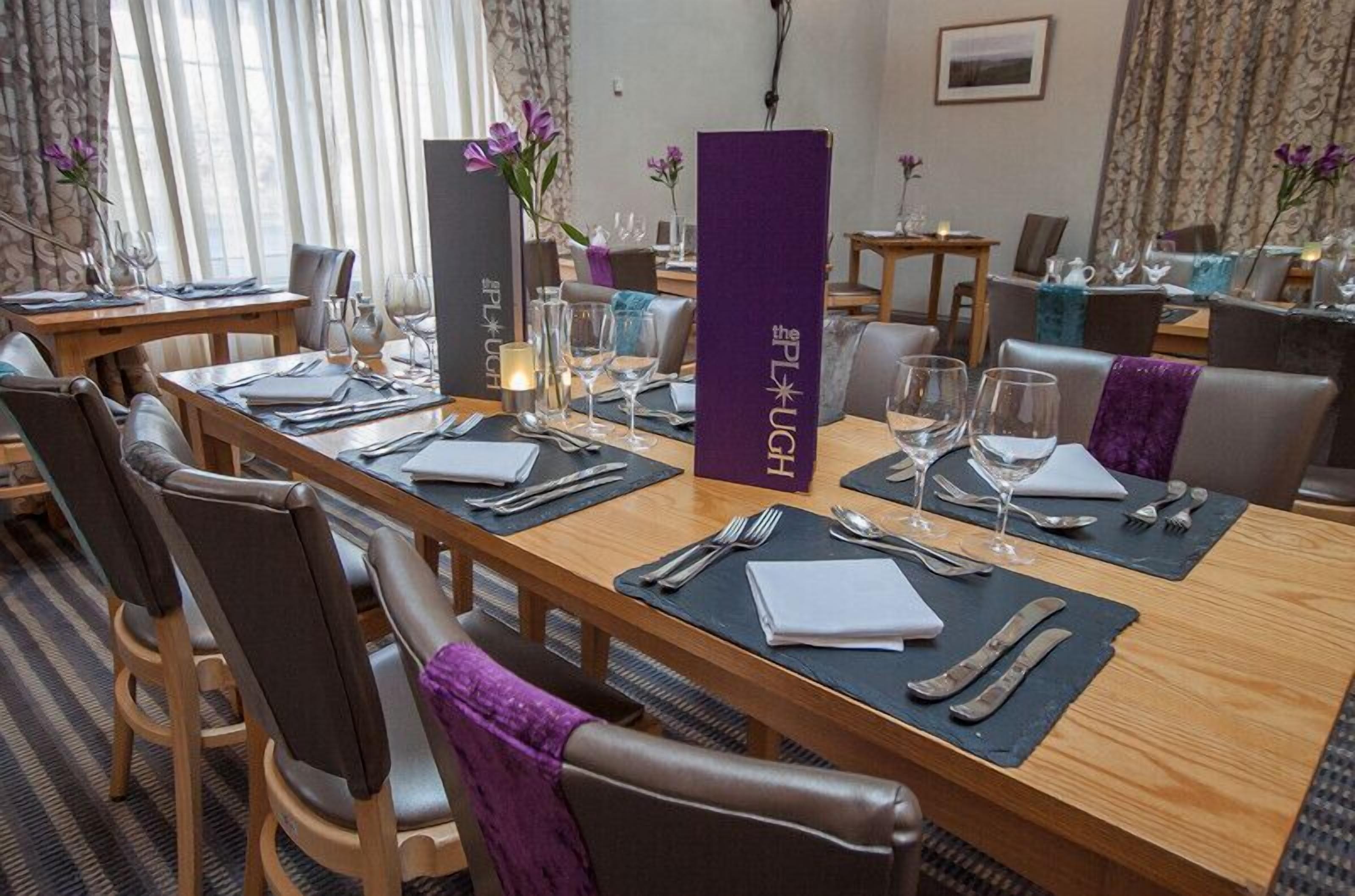 A hotel dining area with wooden tables, purple napkins, and a purple menu stand.
