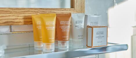 A bathroom shelf with various Bath products including a shower gel, conditioning shampoo, body lotion, and a cleansing bar.