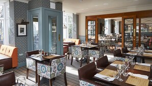 A restaurant with multiple dining tables and chairs, a blue door, and patterned wallpaper. - The Anglesey Arms (Menai Bridge)