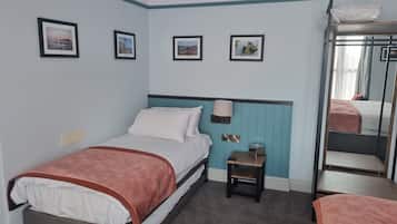 Una habitación de hotel con una cama, una mesita de noche, una lámpara y un espejo.