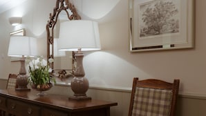 A wooden desk with two lamps, a chair, a mirror, and a framed picture on the wall. - The Anglesey Arms (Menai Bridge)