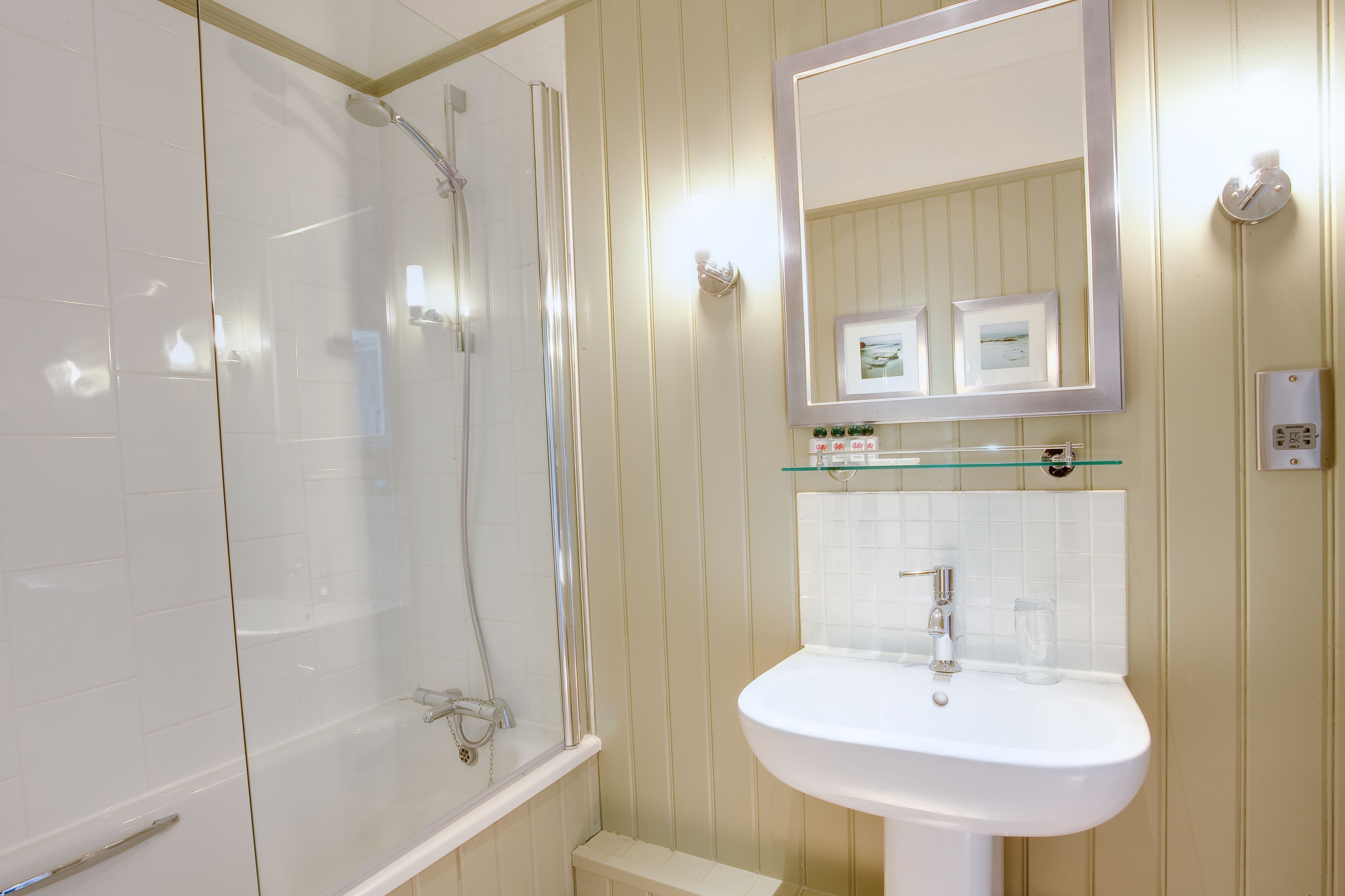 A bathroom with a glass-enclosed shower, a white sink, and a mirror above the sink.