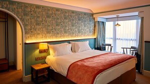 A hotel room with a large bed, a nightstand, a lamp, and a view of the outdoors through a window. - The Anglesey Arms (Menai Bridge)