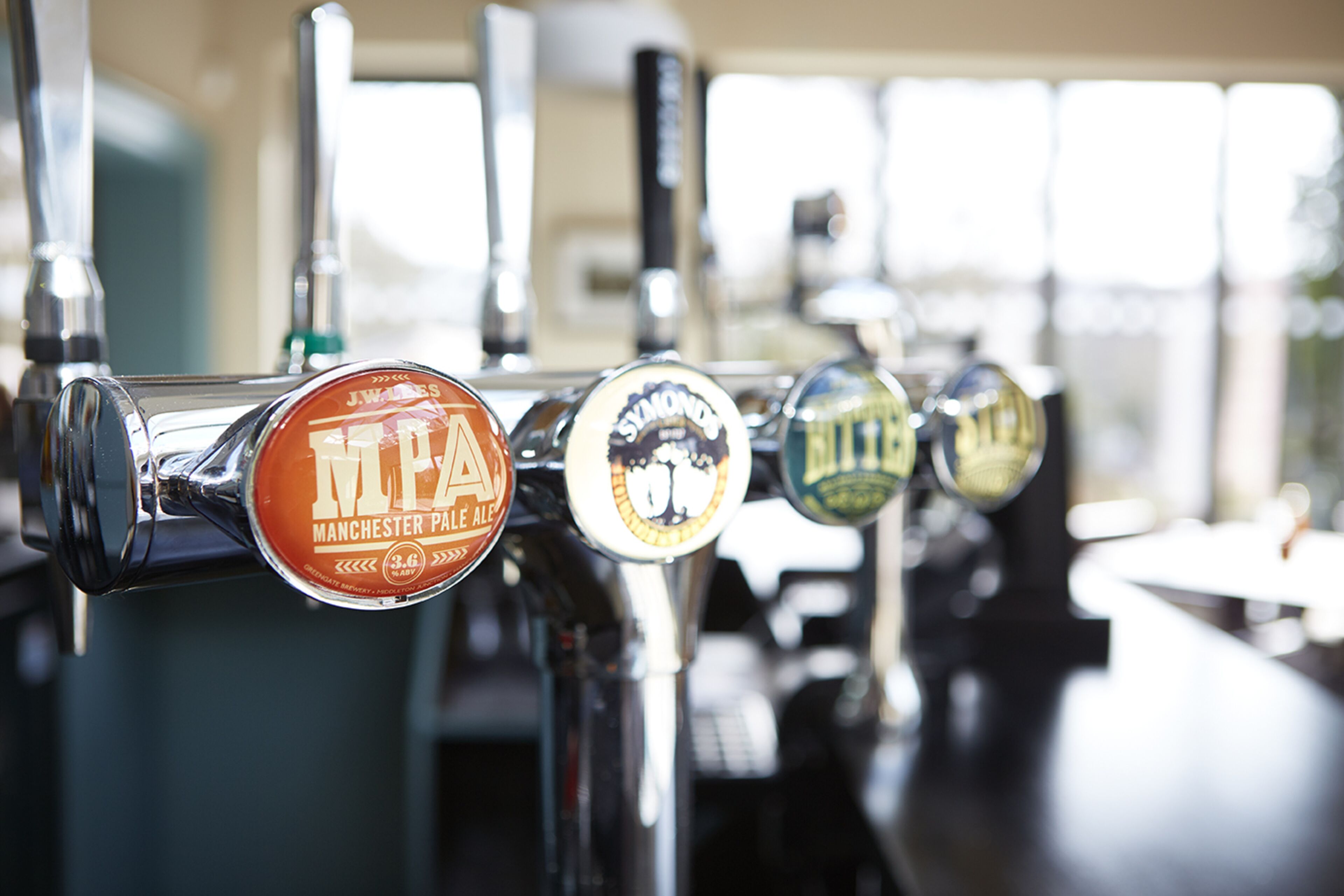 A row of beer taps with labels indicating different types of beer.