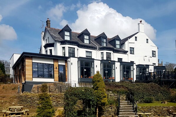 A large, white, two-story building with multiple windows and a stone staircase leading to the entrance. - The Anglesey Arms (Menai Bridge)