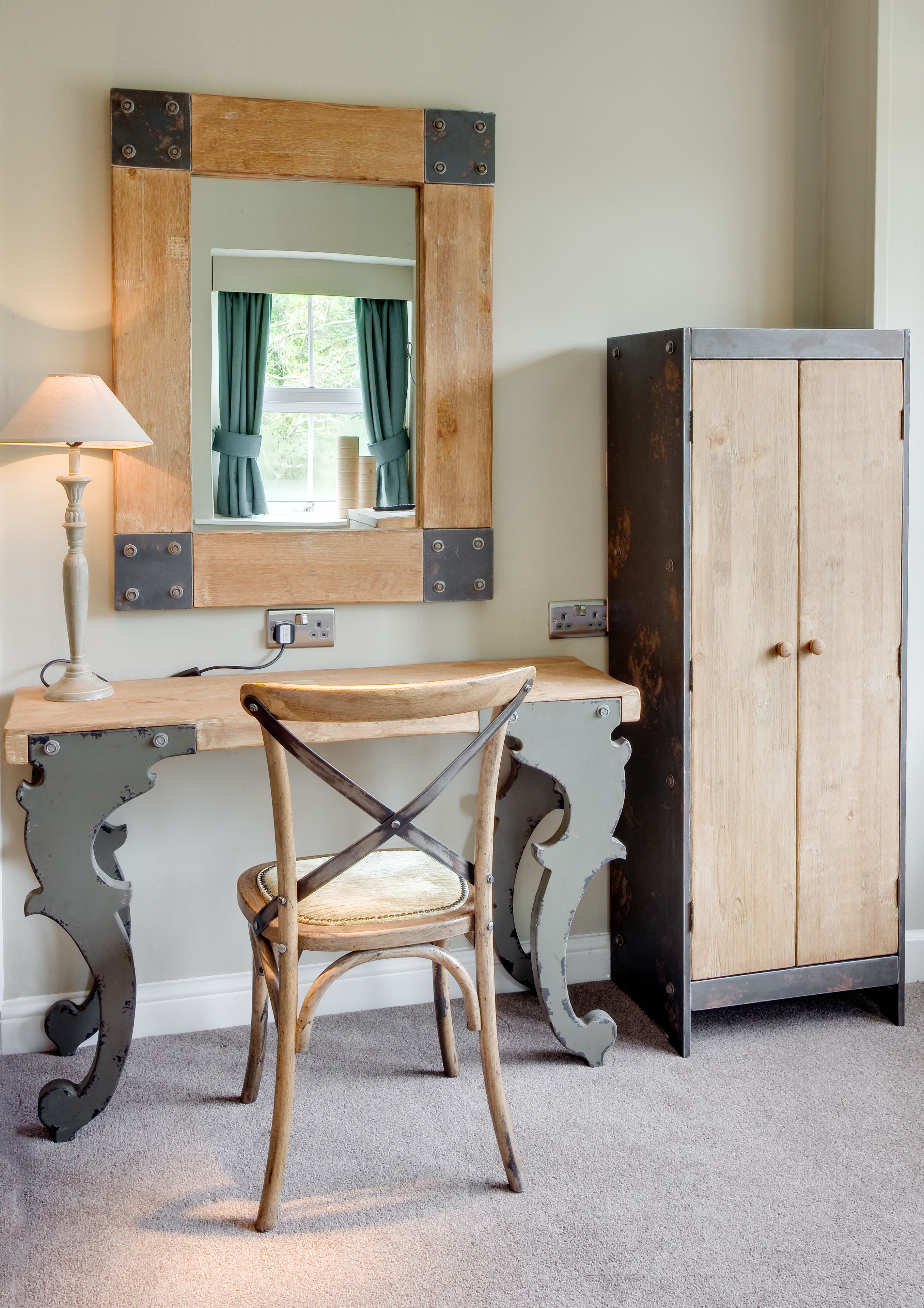 A room with a wooden desk, a chair, a cabinet, and a mirror.