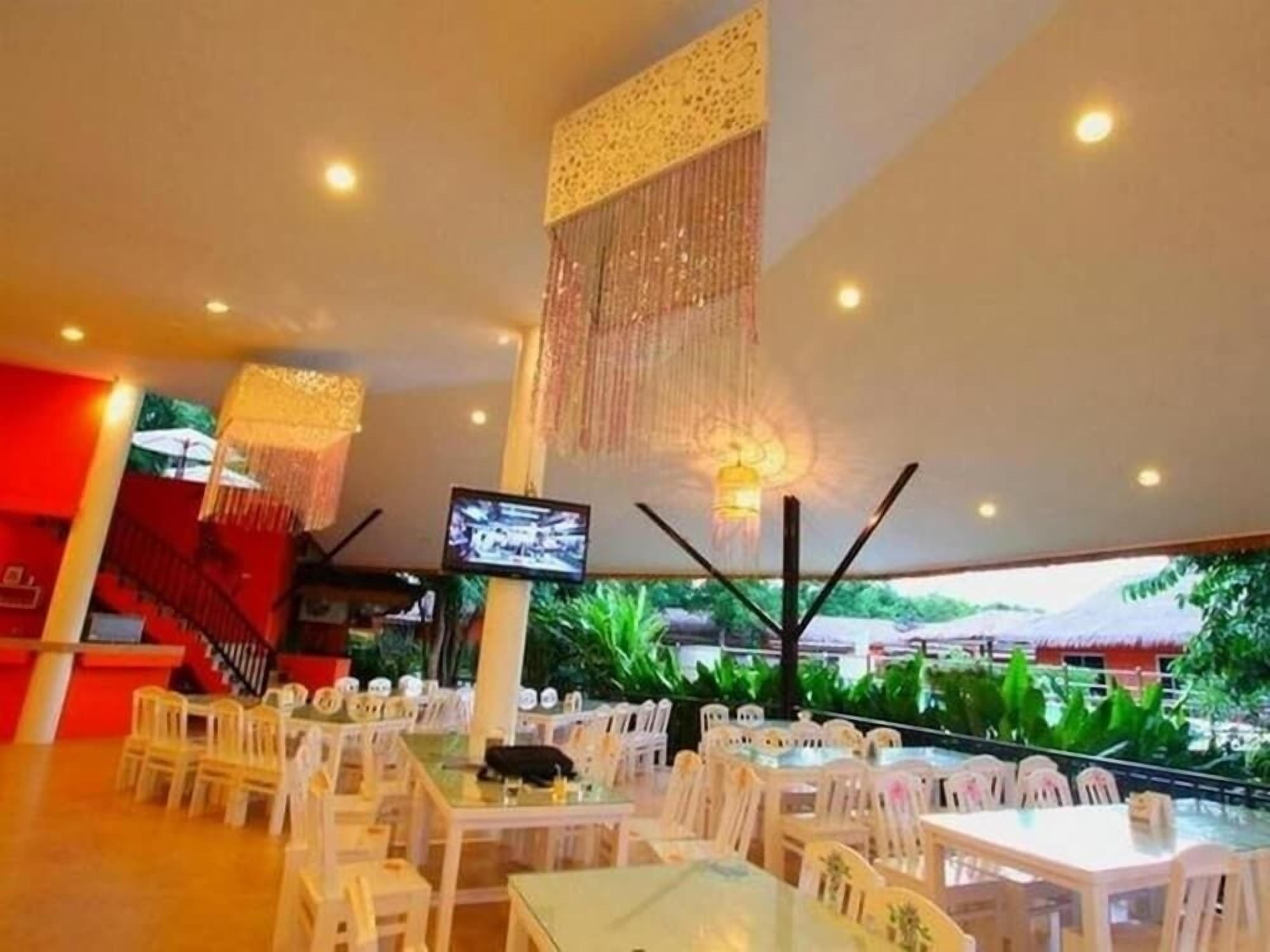 A restaurant with white chairs and tables, a TV screen, and hanging decorations.