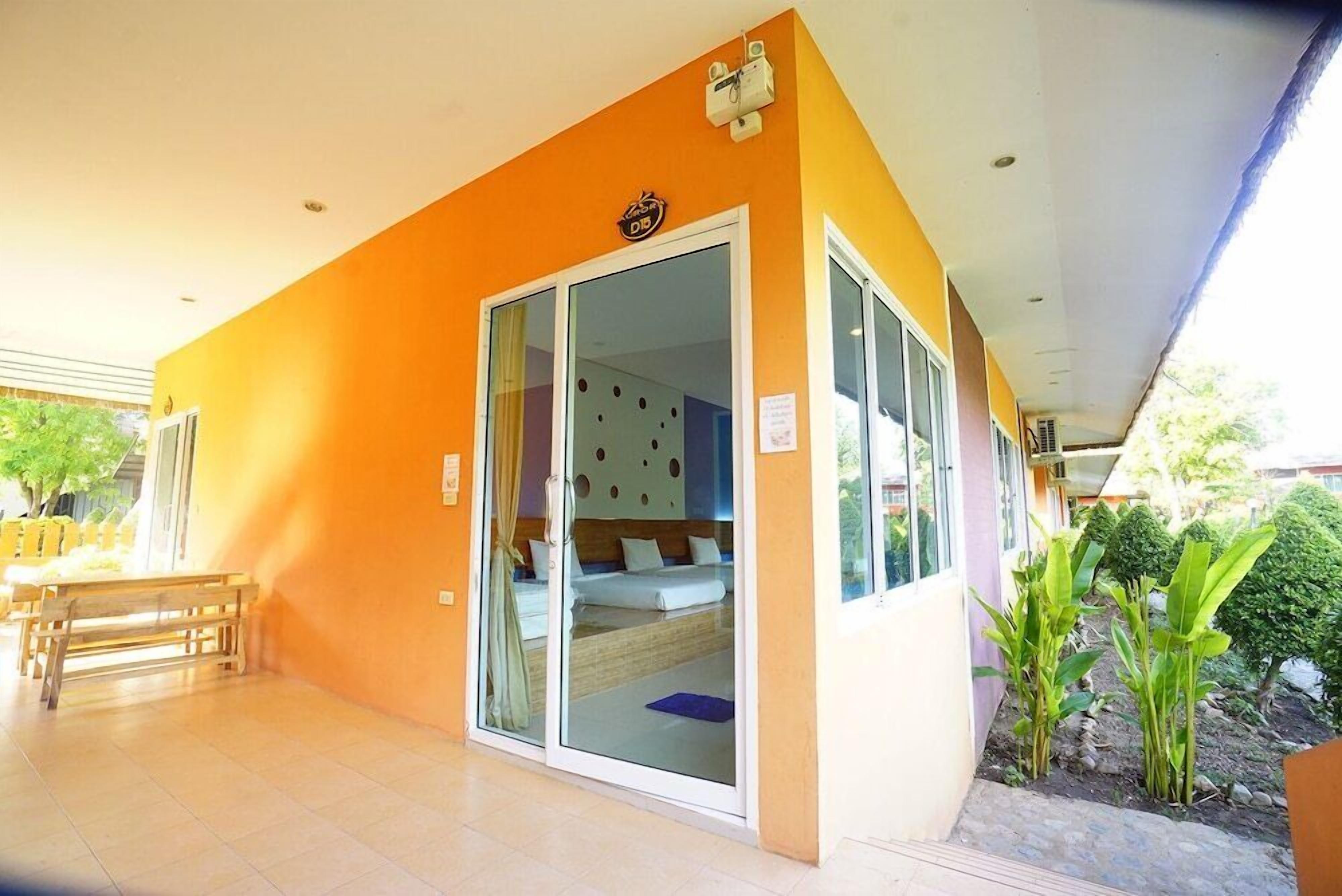 A room with a sliding glass door leading to a bed, a bench, and a small table.