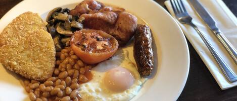A plate of breakfast food including fried eggs, sausages, beans, and a slice of toast.
