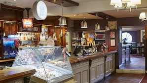 A bar area with a display case of ice cream, a StarSlush machine, and various bottles and glasses on shelves. - New Inn Hotel by Greene King Inns (Newport)
