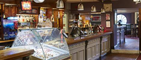 Zona de bar amb una vitrina de gelats, una màquina de StarSlush i diverses ampolles i gots a les prestatgeries.