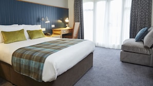 A hotel room with a large bed, a desk, a chair, and a window with curtains. - New Inn Hotel by Greene King Inns (Newport)