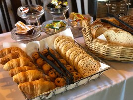 Un bufé con diversas opciones de panadería, incluyendo cruasanes, muffins y pan.