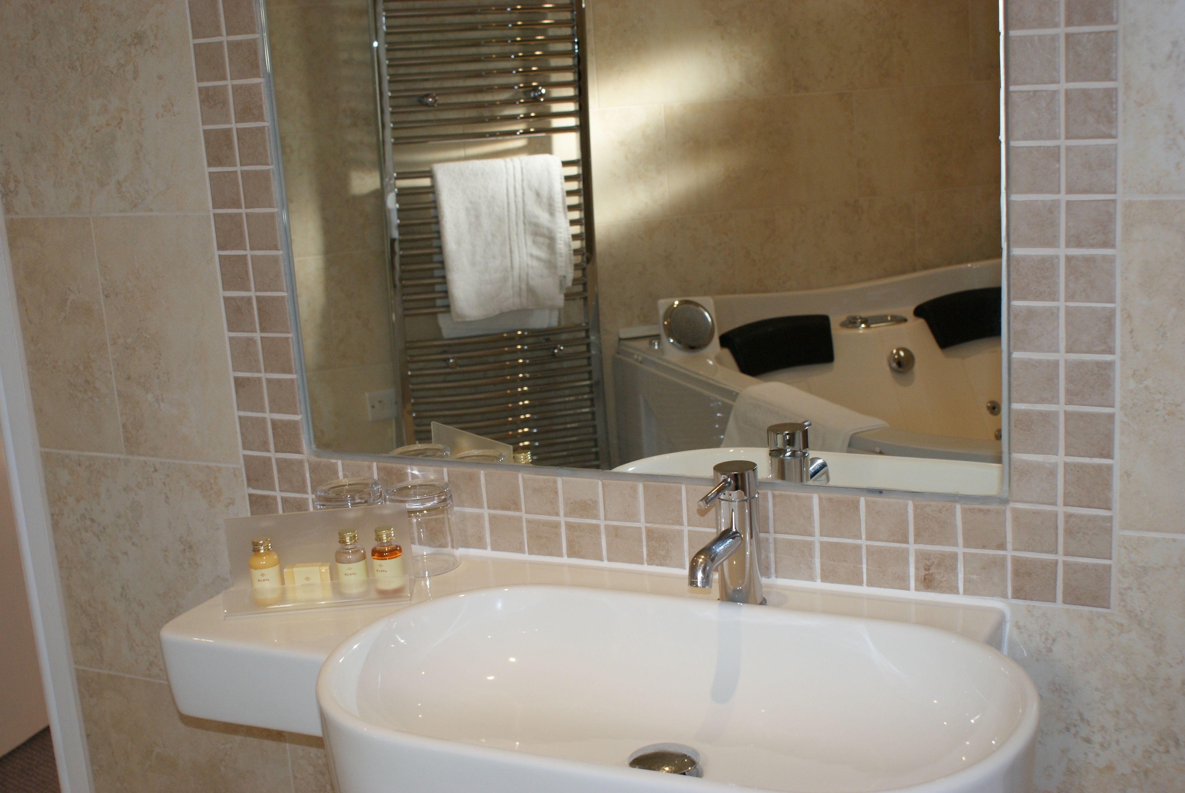 A bathroom with a sink, mirror, and bathtub.