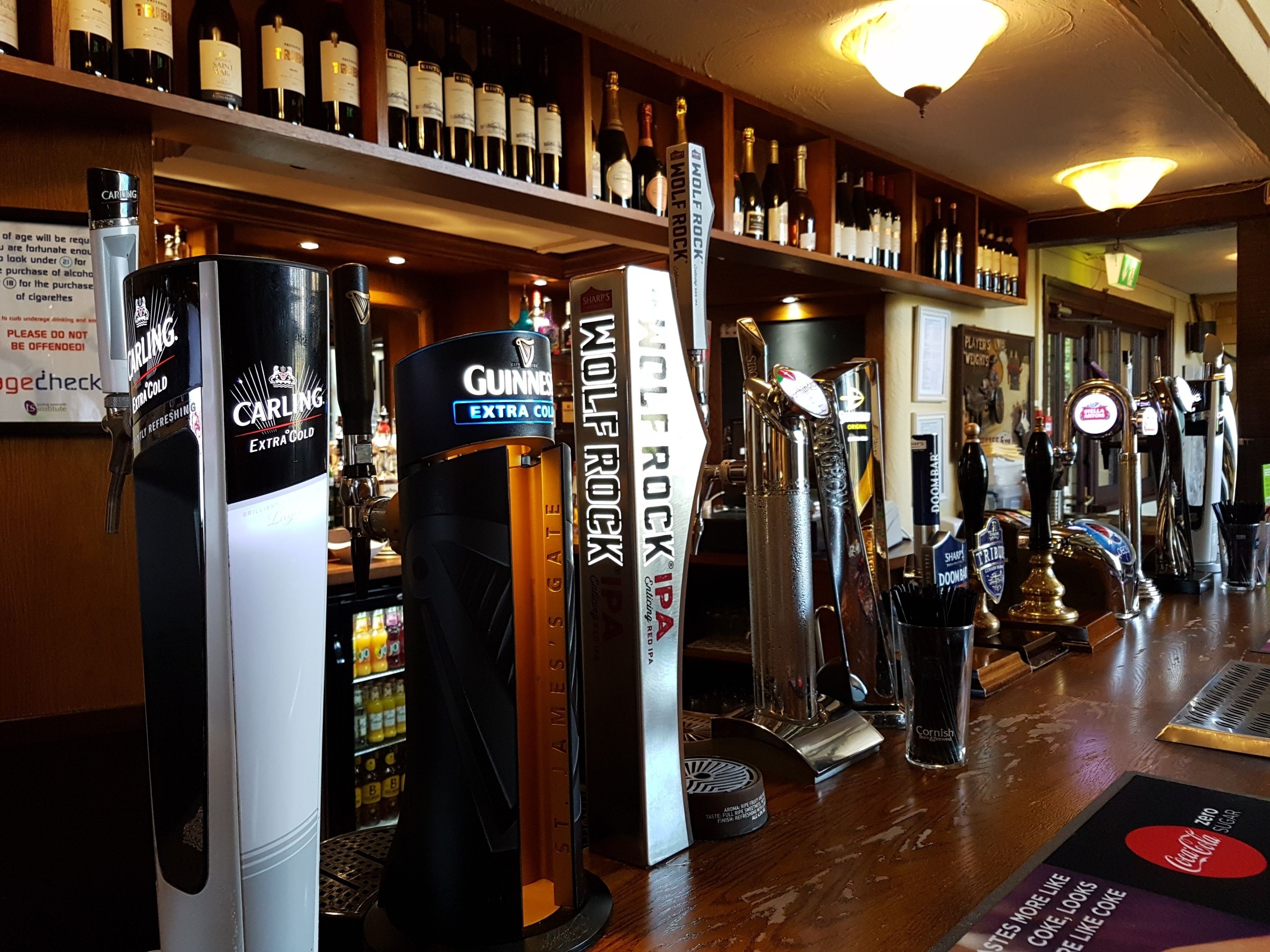 A bar with multiple taps including Guinness, Carling, and Jameson. Shelves with various bottles are visible in the background.