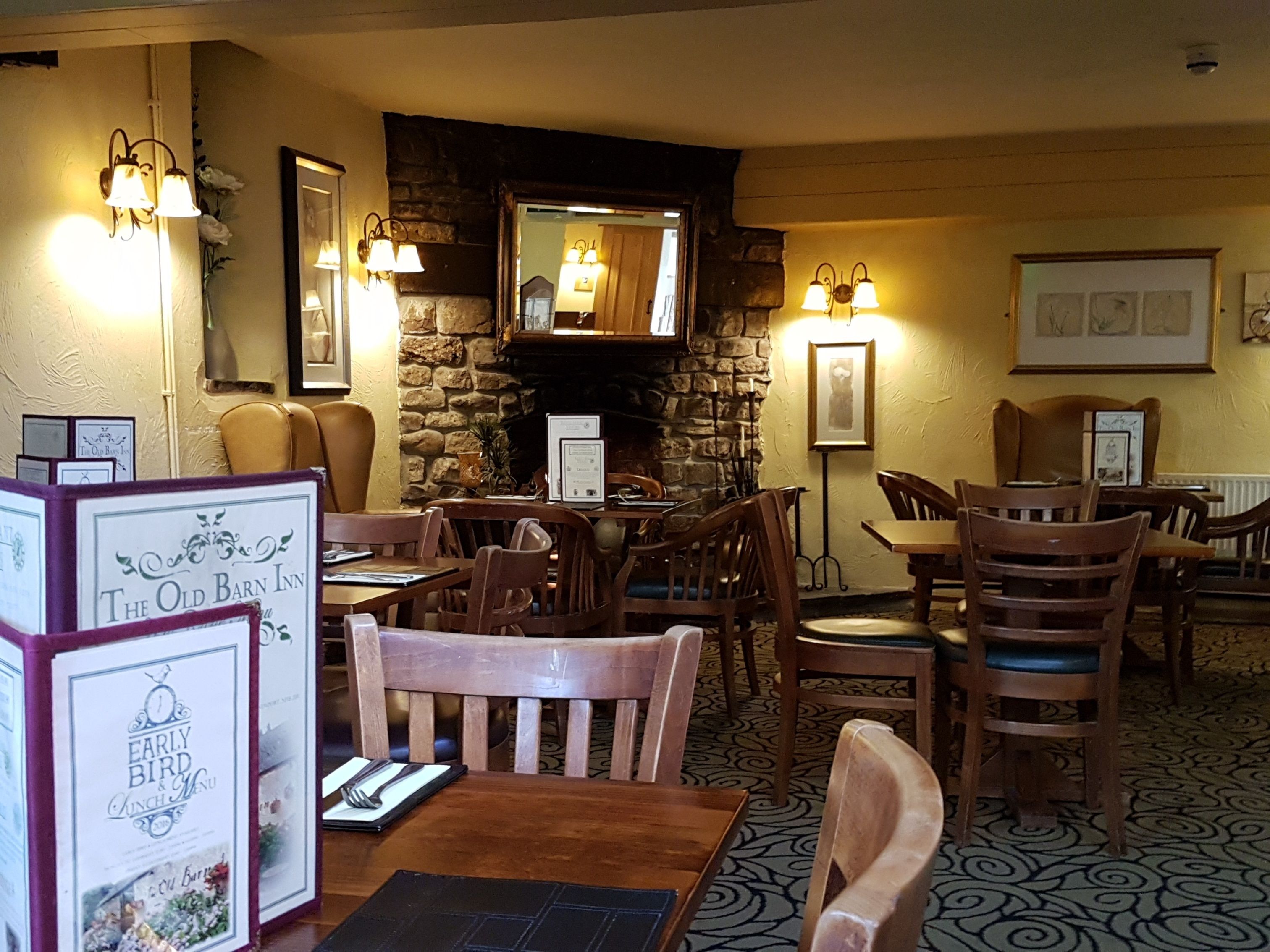 Ein gemütliches Restaurant mit Holztischen, Steinwänden und warmer Beleuchtung.