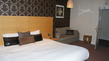 Una habitación de hotel con una cama grande, un sofá, una mesita y una puerta.