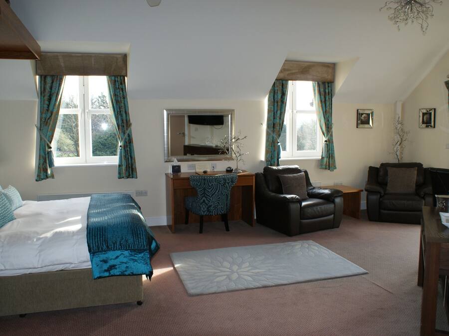 A bedroom with a bed, desk, two chairs, and a television.