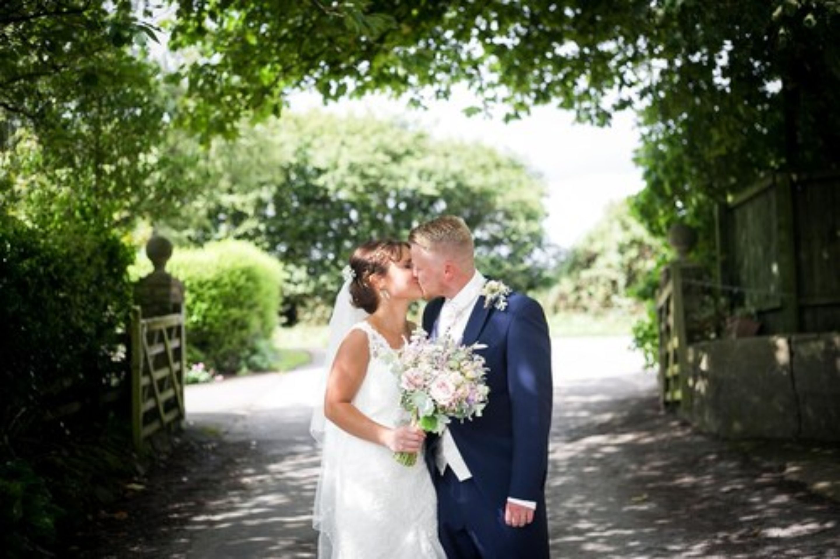 A couple kissing under a tree in a garden setting.