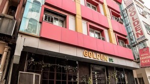 A multi-story building with a prominent "GOLDEN" sign on the ground floor, indicating a hotel. - Golden Deluxe (New Delhi)