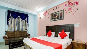 A bedroom with a large bed, a sofa, and a decorative wall. - Golden Deluxe (New Delhi)