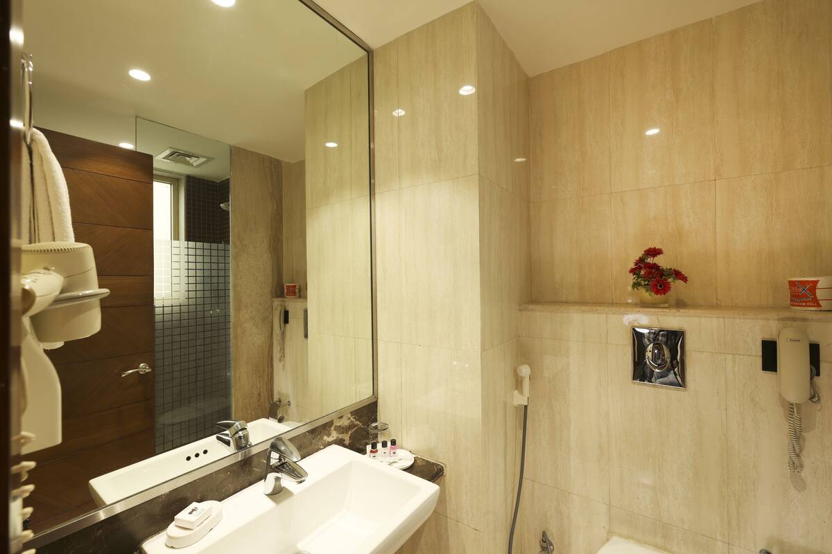 A modern bathroom with a large mirror, two sinks, a shower, and a telephone.