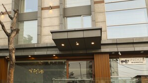 A modern building with multiple balconies, large windows, and potted plants. - Indus Biznotel (New Delhi)