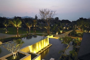 A landscaped area with a water feature, palm trees, and a view of distant mountains. - Pattaya Sea Sand Sun Resort & Spa (Pattaya)