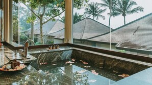 A modern bathroom with a marble sink, a large mirror, and a view of palm trees and houses through the window. - Pattaya Sea Sand Sun Resort & Spa (Pattaya)