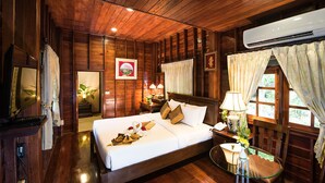 A wooden room with a bed, bedside table, lamp, and an air conditioning unit. - Phuwanalee Resort (Pak Chong)