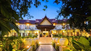 A traditional building with a central entrance, surrounded by lush greenery and decorative lighting. - Phuwanalee Resort (Pak Chong)