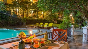 An outdoor dining area with a pool, lounge chairs, and a table set for a meal. - Phuwanalee Resort (Pak Chong)