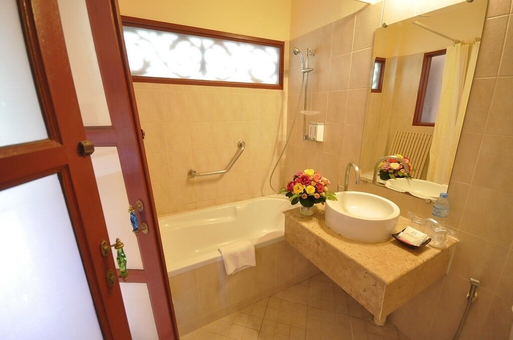 A bathroom with a bathtub, a sink, and a mirror.