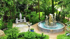 A garden with statues, a fountain, and a white gate. - Phuwanalee Resort (Pak Chong)