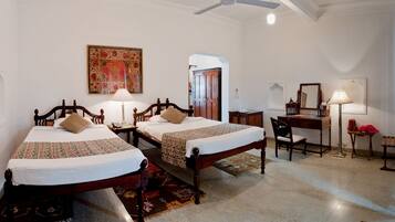 A room with two wooden beds, a desk, a chair, a lamp, and a mirror.