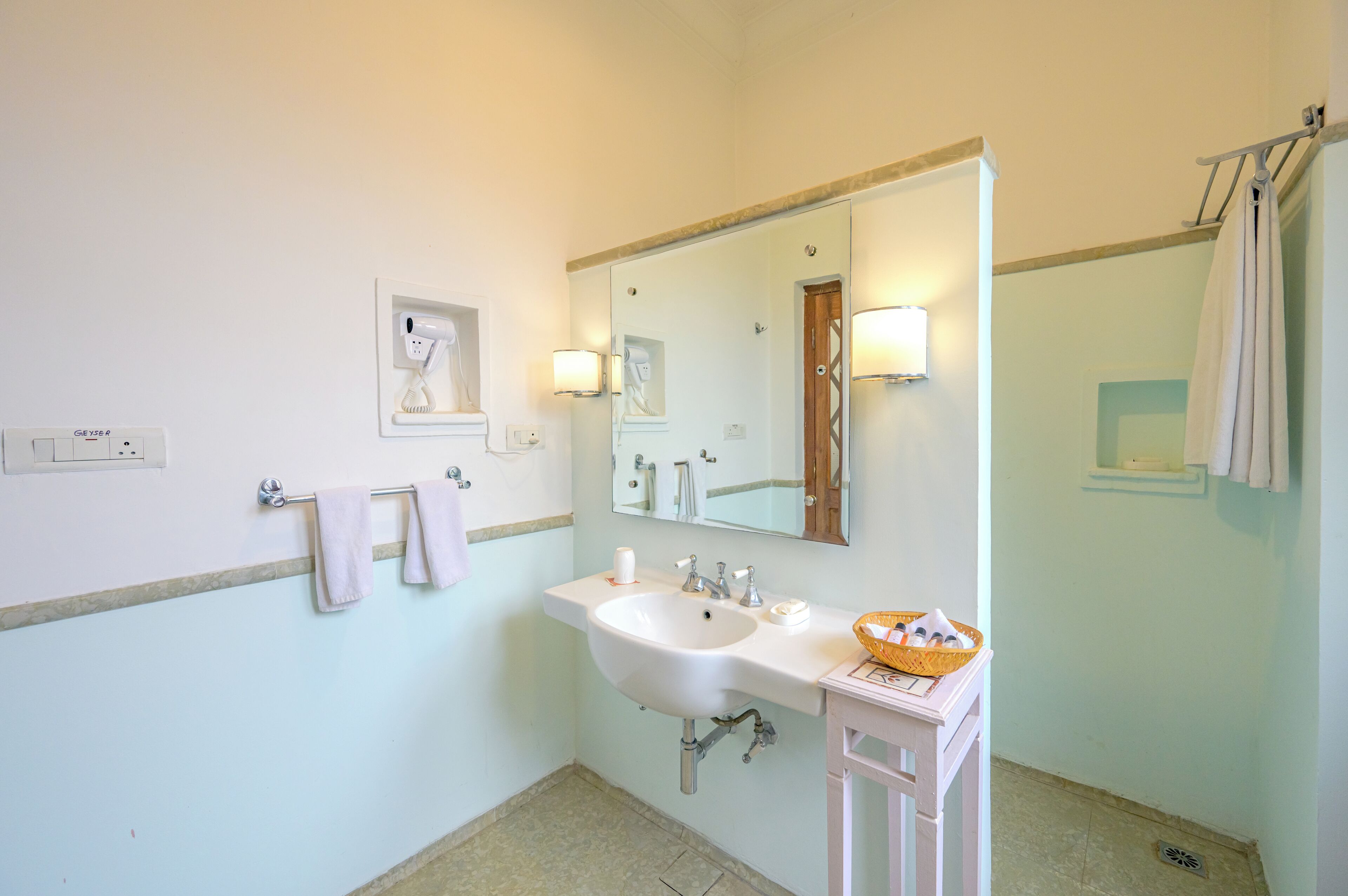 A bathroom with a white sink, a mirror, a towel rack, and a wall-mounted light fixture.