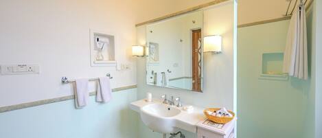 A bathroom with a white sink, a mirror, a towel rack, and a wall-mounted light fixture.