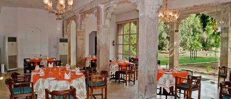 A dining area with tables set for a meal, large windows, and a view of the outdoors.