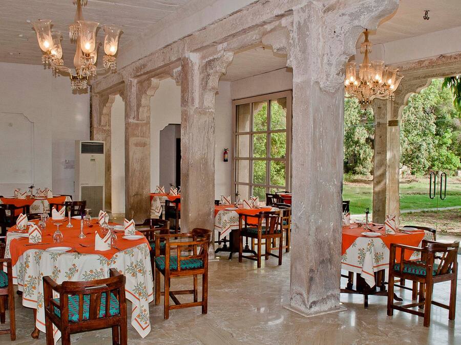 A dining area with tables set for a meal, large windows, and a view of the outdoors.