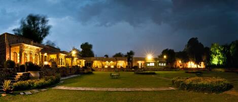 A historic building with illuminated arches and a well-maintained lawn.
