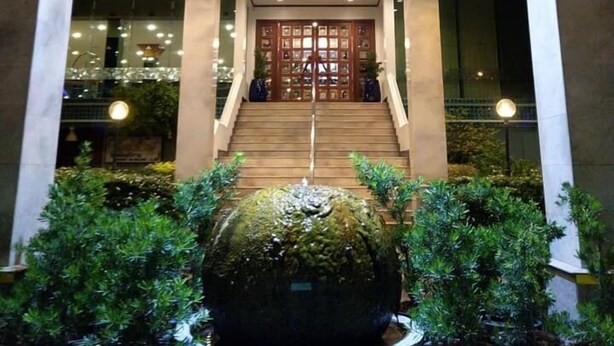 A building entrance with a staircase, a large decorative fountain, and potted plants. - The Viangtak Riverside Hotel (Tak)