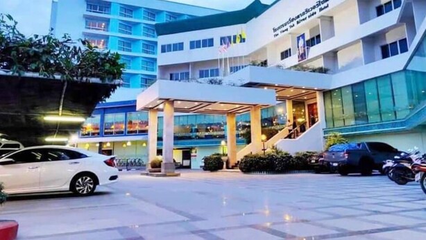 A modern hotel with a multi-story structure, a covered entrance, and a parking area with cars.