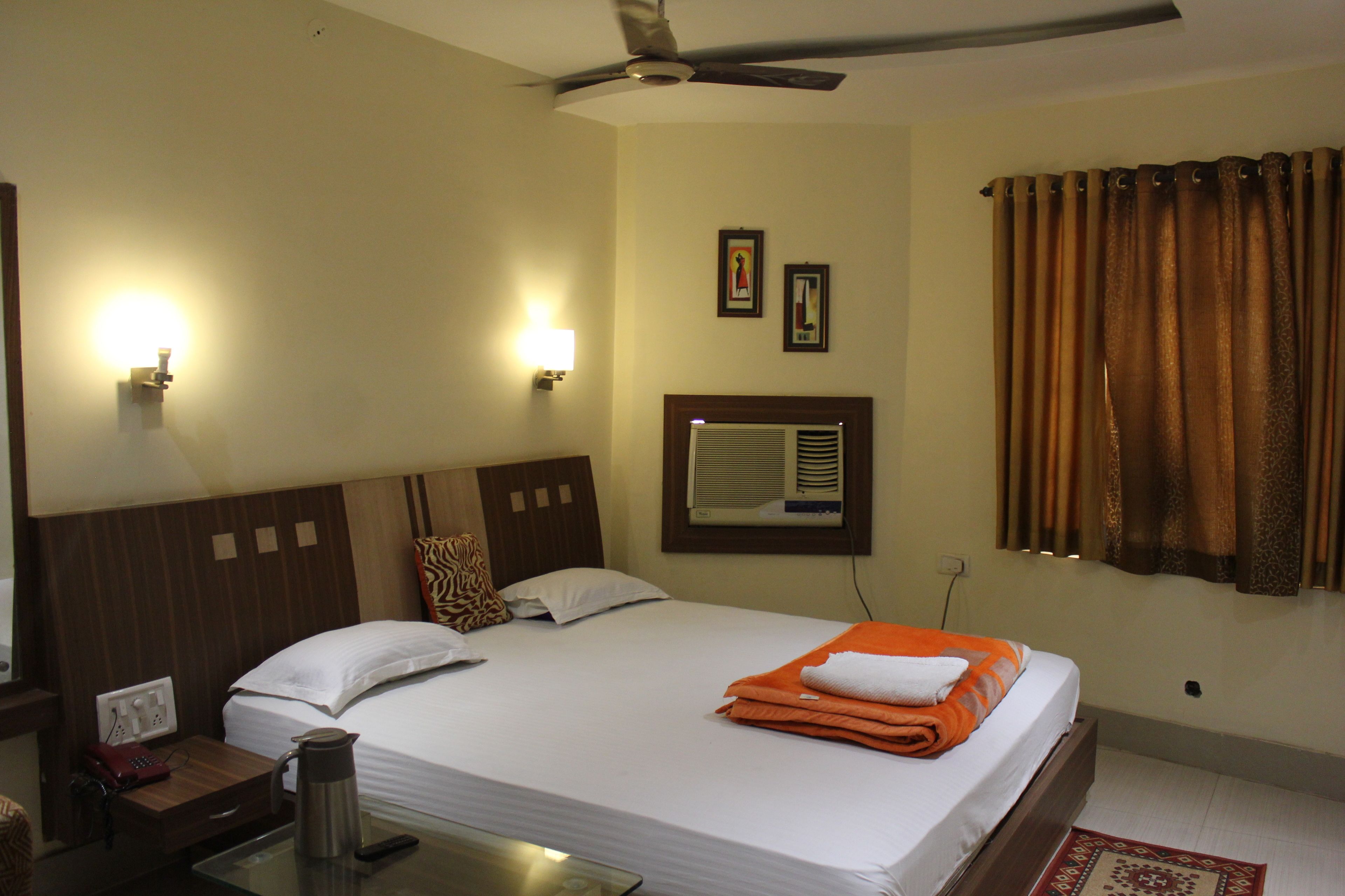 A hotel room with a bed, bedside table, lamp, and ceiling fan.