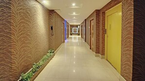 Un couloir d’hôtel aux murs décorés de motifs, doté d’un sol carrelé et de portes des deux côtés.