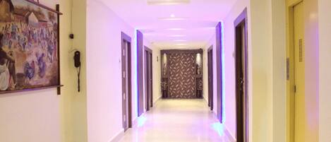 Een hotelgang met een lange corridor, deuren aan beide kanten en een patroon op de achterwand.