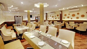 Un restaurant doté de nombreuses tables, chacune étant recouverte d’une nappe blanche et agrémentée de couverts en argent.