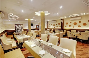 Un restaurante con varias mesas de comedor, cada una con manteles blancos y cubiertos.